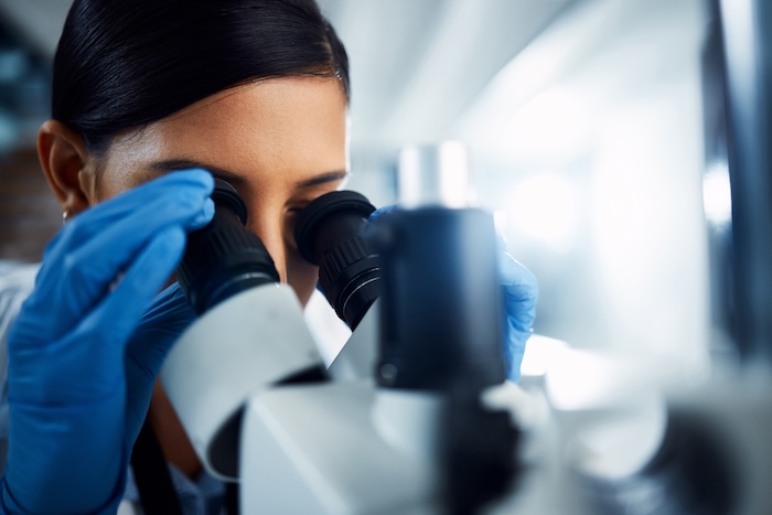 scientist looking through microscope